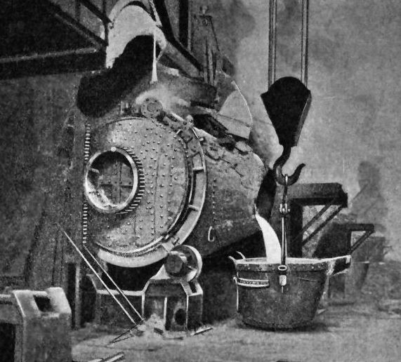 A converter tipped to pour slag into a pot below
